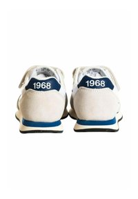 Scarpe atletiche bianche con dettagli in suede beige, rifiniture blu sul tallone e il numero "1968" sul tallone. Texture morbida e design arrotondato.