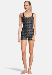 Maillot de bain à motifs noir et gris avec un col rond et des bretelles larges, présentant une coupe ajustée et des jambes courtes. Texture de tissu lisse.