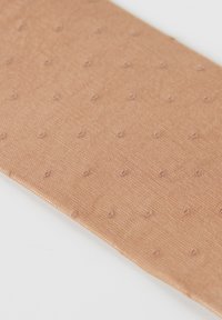 Tela de color beige claro con una superficie texturizada que presenta pequeños puntos en relieve. El material parece ser tejido, ofreciendo un acabado suave y un ligero brillo.