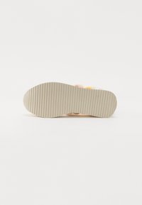 Semelle de chaussure en caoutchouc beige texturé avec des rainures horizontales ; le design comprend des couleurs pastel dans la section supérieure.