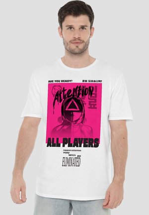 White t-shirt featuring a bold pink graphic with text "Attention ALL PLAYERS" and an illustration of a person in a hooded mask.