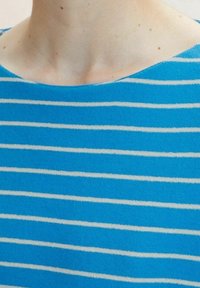 Top in maglia blu con strisce orizzontali bianche, caratterizzato da un ampio scollo e una texture morbida, concentrandosi sulla semplicità e sul comfort nel design.