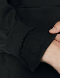 Must mustri pehmest ja karvast sisemusest, millel on ribbikujundusega tekstuur. Õmblused on nähtavad varruka servadel.