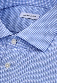 Camicia azzurro chiaro con motivo a tessitura, collo piccolo e bottoni bianchi. L'etichetta riporta "seidensticker."