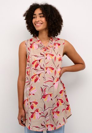 Mouwloos topje van lichtbeige stof, met een bloemmotief in roze, rood en oranje tinten, en een geplooide halslijn.