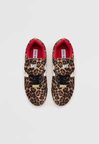 Leopard print sneakers with a textured fabric upper, black laces, red lining, and silver hardware on the strap and tongue.