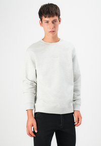 Light grey sweatshirt with a crew neckline, ribbed cuffs, and waistband. Features an embossed logo on the chest and a soft texture.