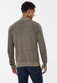 Pull en tricot gris avec un col montant et des manches longues. Doté de poignets et d'un ourlet côtelés, texture douce et coupe décontractée.