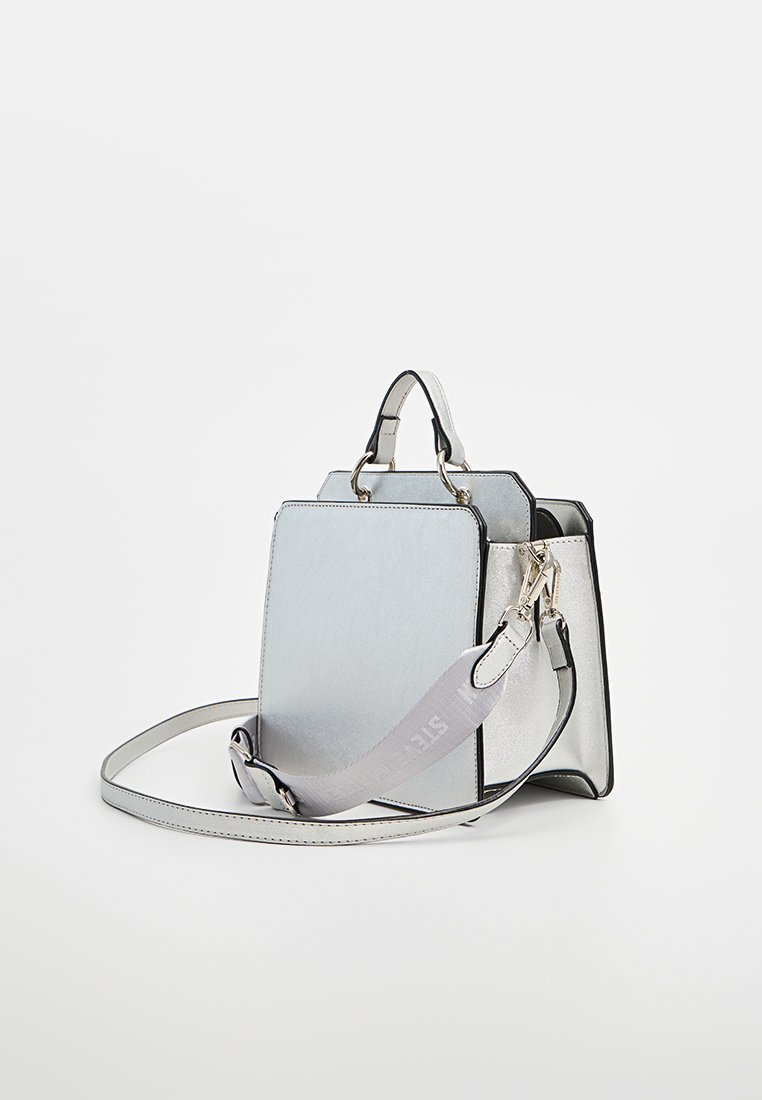 Sac à main en argent métallisé avec un design structuré, deux courtes poignées et une sangle d'épaule réglable. Texture lisse avec des détails noirs contrastants.