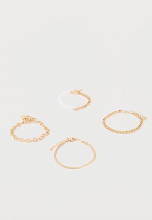 Ensemble de quatre bracelets en or sur fond blanc, comprenant des maillons de chaîne, des perles et différents styles de fermoirs.