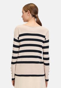 Gebreide trui met een beige en marineblauwe gestreepte patroon, voorzien van een ruime halslijn en knopenaccenten op de manchetten. Zachte textuur, ontspannen pasvorm.