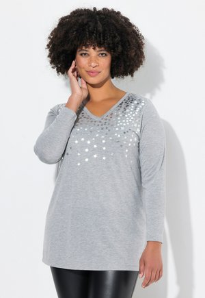 Chemise grise à manches longues et en V avec des motifs d'étoiles argentées sur les épaules. Matière douce, coupe décontractée, s'associe avec des leggings ajustés.