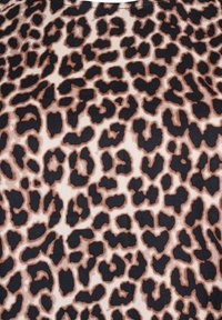 Leopardi prindiga kangas, kus ebaregulaarne must ja pruun laik on beežil taustal, luues julge loomamustri.
