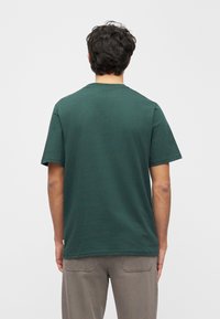 Ciemnozielona koszulka z krótkim rękawem i okrągłym dekoltem, wykonana z miękkiego materiału, o luźnym kroju i gładkim wzorze bez nadruków.