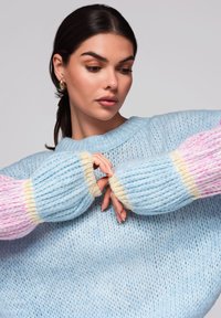 Maglione azzurro chiaro lavorato a maglia con maniche oversize multicolori in rosa e accenti giallo tenue, caratterizzato da una texture a coste in tutta la sua superficie.