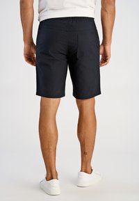 Granatowe spodenki z elastycznym pasem, pojedynczą kieszenią z tyłu i obszytymi krawędziami, zestawione z białymi trampkami.