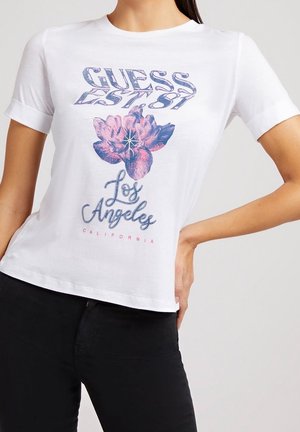 Hvid kortærmet T-shirt med opbukket kant, med pink og blå blomst og teksten "GUESS EST 81 Los Angeles California."