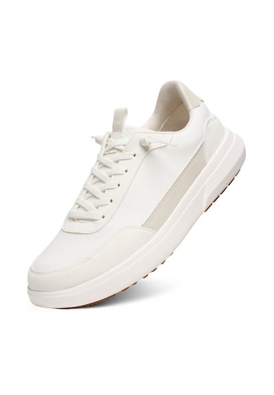 Zapatilla blanca con parte superior de tejido texturizado, cierre con cordones y suela suave y acolchada. Presenta sutiles detalles en gris en el lateral.