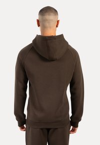 Sudadera con capucha de color marrón oscuro y textura suave, con mangas raglán y dobladillo acanalado, diseñada para la comodidad y facilidad de movimiento.