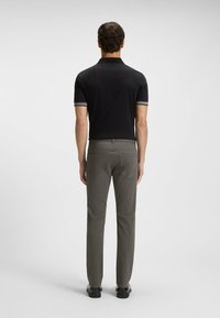 Czarna koszulka polo z szarym kołnierzykiem i akcentami na rękawach, zestawiona z szarymi spodniami. Prosty, dopasowany krój i gładka tekstura.