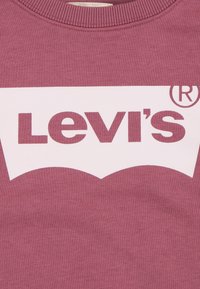 Felpa color bordeaux con logo bianco di Levi's. Presenta un collo rotondo e una trama morbida. Design semplice senza ulteriori grafiche o decorazioni.