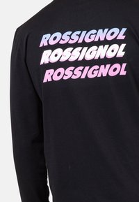 Schwarzes Langarmshirt mit mehreren "ROSSIGNOL"-Logos in einem Farbverlauf aus Pink und Blau, die auf der Rückseite auffällig platziert sind.
