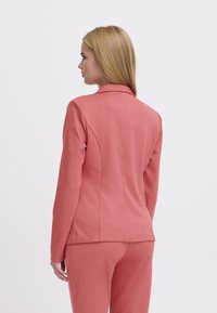 Op maat gemaakte blazer in koraalstof met een gladde textuur, gelobde kraag en gestructureerde naden. Gekocht over bijpassende broek.