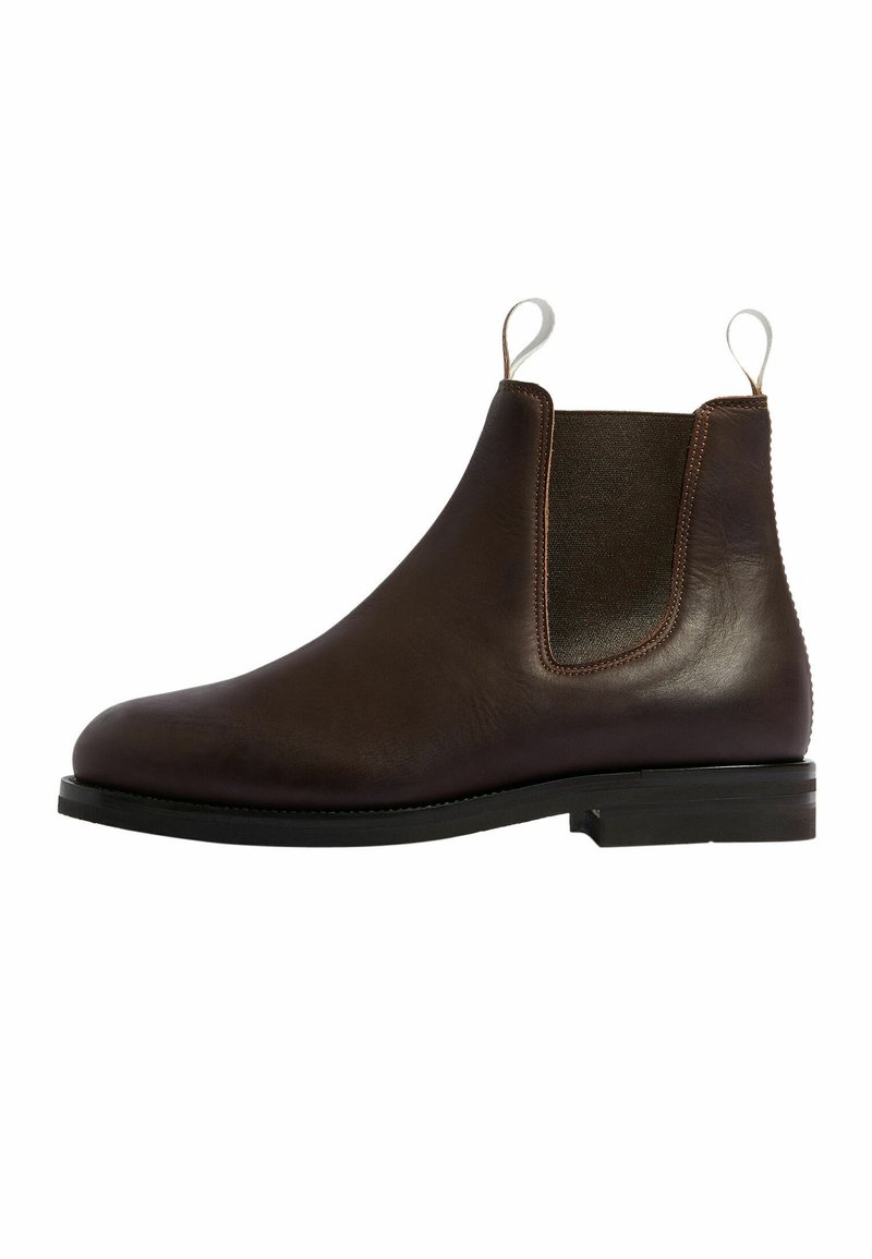 Bota Chelsea de cuero marrón con paneles laterales elásticos, un acabado suave, suela plana negra y tiradores para facilitar el calzado, que muestra un diseño clásico.