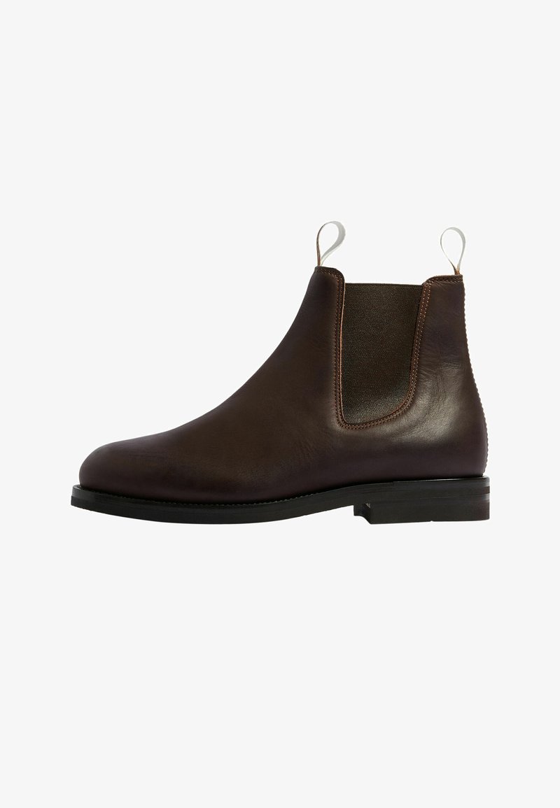 Bota Chelsea de cuero marrón con paneles laterales elásticos, un acabado suave, suela plana negra y tiradores para facilitar el calzado, que muestra un diseño clásico.
