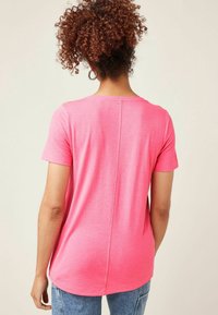 Lyserød t-shirt med korte ærmer og rund halsudskæring, lavet af blødt stof, med en midtersøm på bagsiden og en afslappet pasform.