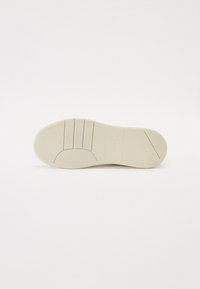 White rubber shoe sole with horizontal grooves and a textured finish. Logo embossed near the heel. Smooth edges and rounded toe.