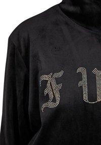 Suéter de cuello alto negro y suave con una superficie texturizada que presenta acentos de strass formando letras estilizadas. Corte relajado, mangas largas.