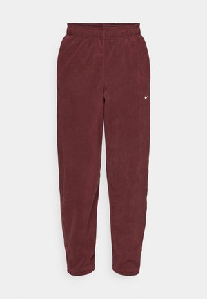 Bordeauxfarbene Fleece-Sweatpants mit einem elastischen Bund und einem weißen Nike-Logo auf dem linken Oberschenkel. Schmal zulaufende Beine mit einer glatten Textur.