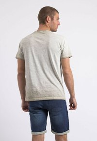 T-shirt crème à manches courtes avec une finition texturée, associé à un short en denim foncé avec des ourlets retroussés et des poches arrière.