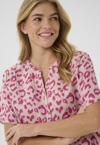 Camicia a maniche corte, con stampa leopardata rosa, bottoni a pressione e scollatura rotonda, realizzata in tessuto testurizzato e con bottoni in legno naturale.