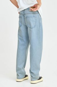 Vaqueros de mezclilla de color azul claro con un corte holgado, que cuentan con dos bolsillos traseros y un diseño clásico de cinco bolsillos. Textura suave y estilo casual.