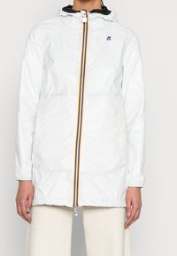 Weiße wasserdichte Jacke mit Kapuze, ausgestattet mit einem Frontreißverschluss mit blauen, gelben und roten Streifen sowie elastischen Bündchen für eine verstellbare Passform.