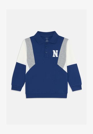 Polo de manga longa azul-marinho com painéis cinza e branco, colarinho com três botões e a letra "N" branca no peito. Material em mistura de algodão.