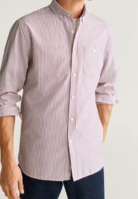 Rood-wit gestreepte blouse met een klassieke kraag, een borstzak, en lange mouwen opgerold bij de manchetten.