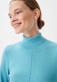 Maglione a collo alto lavorato a maglia di colore azzurro chiaro, con un design aderente. Presenta una texture liscia e un colletto a coste. Dettaglio delle cuciture visibile sul davanti.