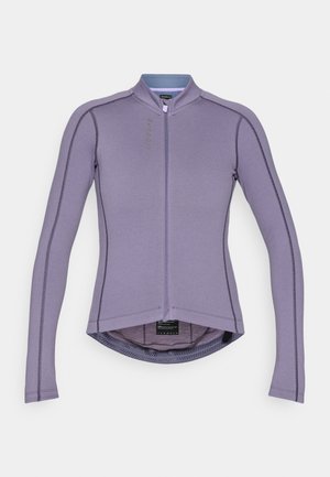 Purpura ilga piedziņas krekls ar augstu apkakli, priekšējo rāvējslēdzēju un kontrastējošiem šuvēm. Iespējas ietver noapaļotu malu un elpojošu audumu.