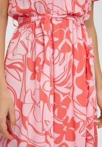 Rosa Kleid mit großen, fließenden Blumenmustern in dunklerem Rosa, einem gebundenen Taillenspiegel und weichem, leichtem Stoff.