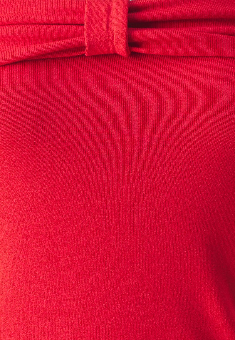 Roter Stoff mit geripptem Muster, der an der Taille mit einem verdrehten Knotendetail verziert ist. Glatte Oberfläche mit gleichmäßigen Nähten.