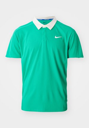 Polo vert en tissu texturé, avec un col blanc, des manches courtes et un petit logo Nike argenté sur la poitrine gauche.