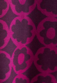 Tessuto viola con motivo floreale nelle tonalità di magenta, caratterizzato da grandi forme floreali intervallate da forme decorative.