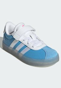 Baskets bleues avec des accents blancs, dotées d'une sangle velcro, en cuir lisse et en daim, et d'une semelle en caoutchouc translucide.