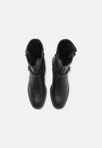 Bottines en cuir noir avec bout arrondi, finition lisse, fermeture éclair latérale et détails en m étal doré.