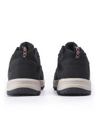 Musta urheilukengät, joissa on verkko-osa, pehmustetut kantapää ja kontrastoivat beiget välikengät. Sisältää kuviollisia yksityiskohtia kantapäässä ja nauhoituksessa.