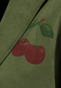 Groene suède stof met een zachte textuur, met een ontwerp van rode kersen, inclusief twee kersen en groene bladeren.