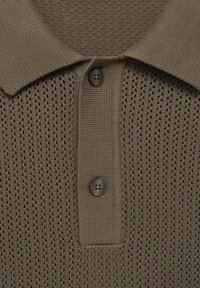 Polo shirt in maglina marrone con un motivo testurizzato, tre bottoni e colletto classico. Il materiale è traspirante con un design simile a una rete.